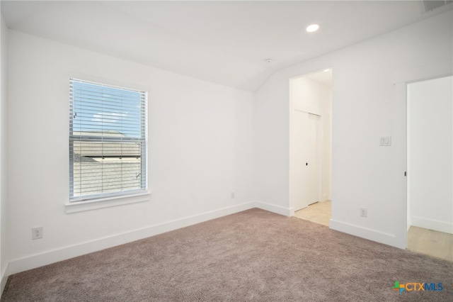 carpeted empty room featuring vaulted ceiling