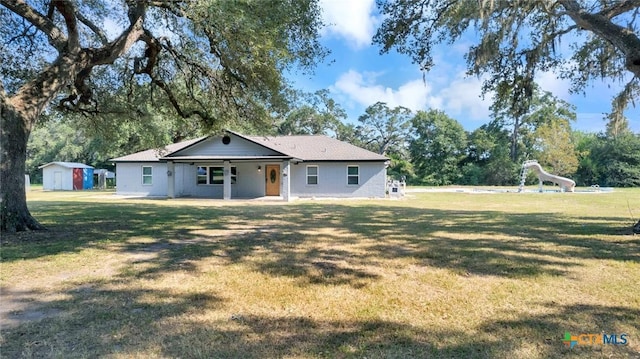 rear view of property with a yard and a storage unit