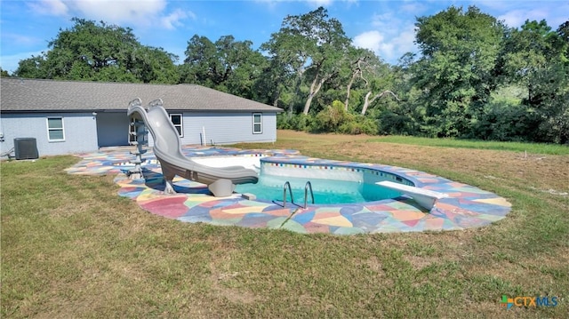 view of pool with a yard, central AC, a diving board, and a water slide