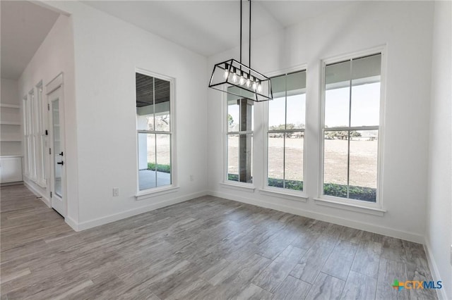 unfurnished dining area featuring wood finished floors and baseboards