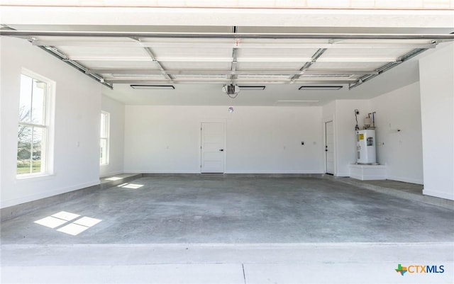 garage featuring electric water heater, a garage door opener, and baseboards