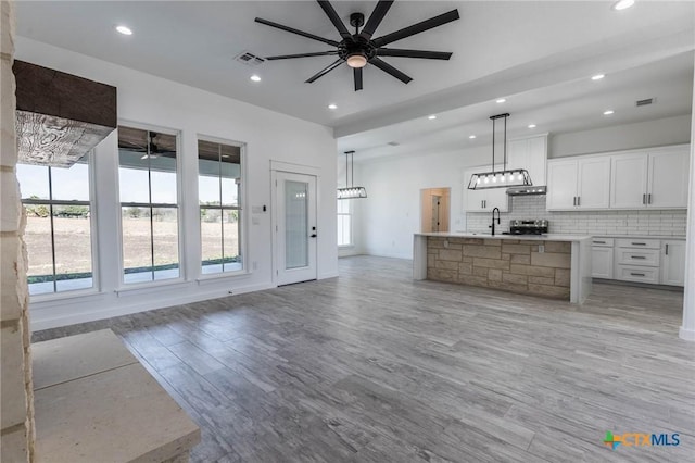 kitchen with visible vents, tasteful backsplash, open floor plan, white cabinets, and ceiling fan