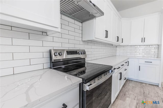 kitchen with stainless steel electric range oven, light stone counters, decorative backsplash, custom range hood, and white cabinetry