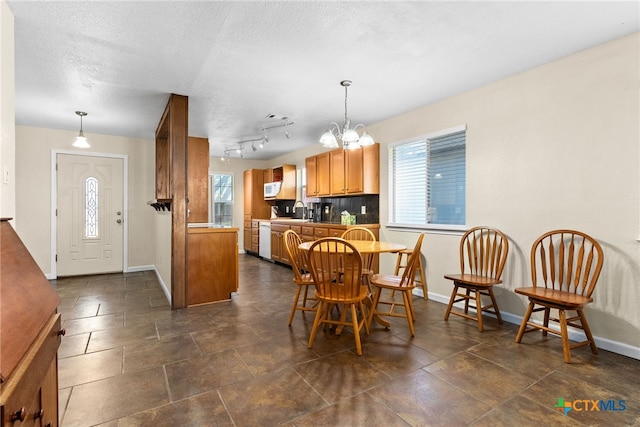 dining area featuring a healthy amount of sunlight, a notable chandelier, baseboards, and a textured ceiling