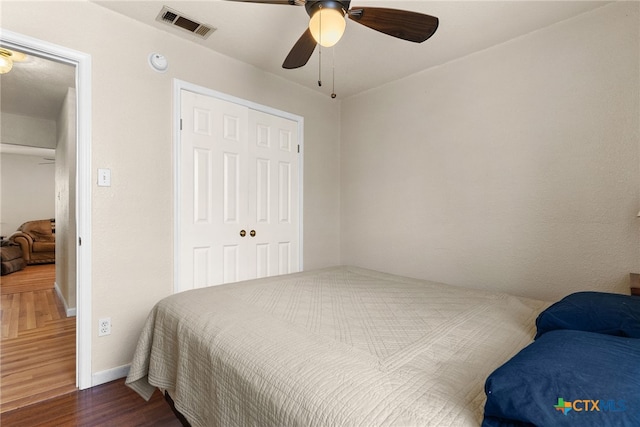 bedroom with visible vents, baseboards, a ceiling fan, dark wood-style floors, and a closet