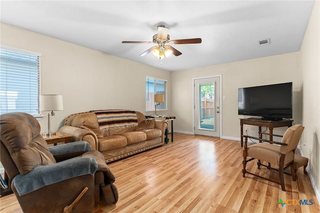 living room with a ceiling fan, visible vents, light wood-style flooring, and baseboards