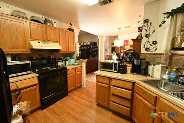 807 Hartrick Cir, Temple, TX 76502 - kitchen with black stove, under cabinet range hood, stainless steel microwave, and light countertops