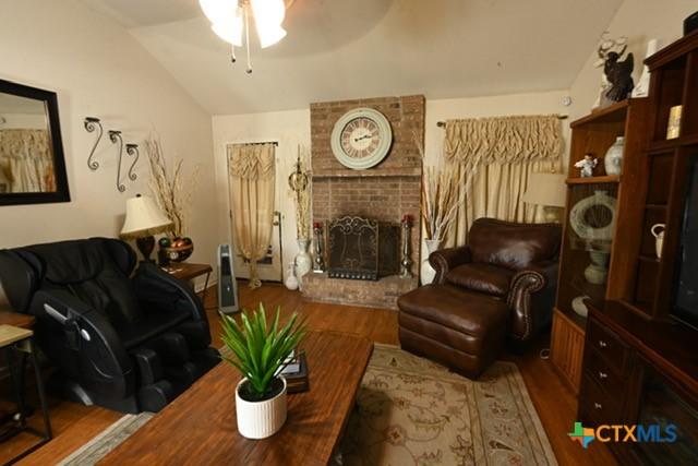 807 Hartrick Cir, Temple, TX 76502 - living room with vaulted ceiling, a ceiling fan, wood finished floors, and a brick fireplace