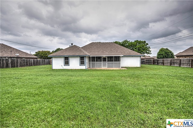 rear view of property featuring a lawn and a sunroom