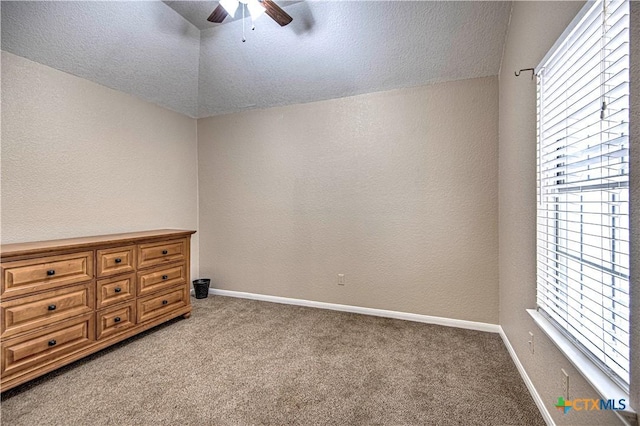 spare room featuring ceiling fan, carpet flooring, vaulted ceiling, and a textured ceiling