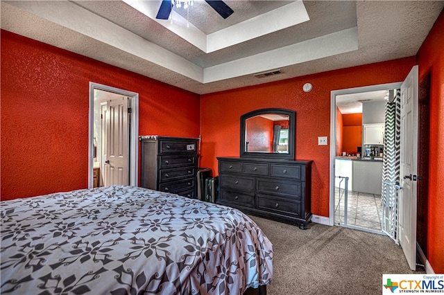 bedroom featuring a tray ceiling, a textured ceiling, carpet flooring, and ceiling fan