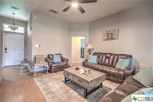 living room with a textured ceiling, light hardwood / wood-style floors, and ceiling fan