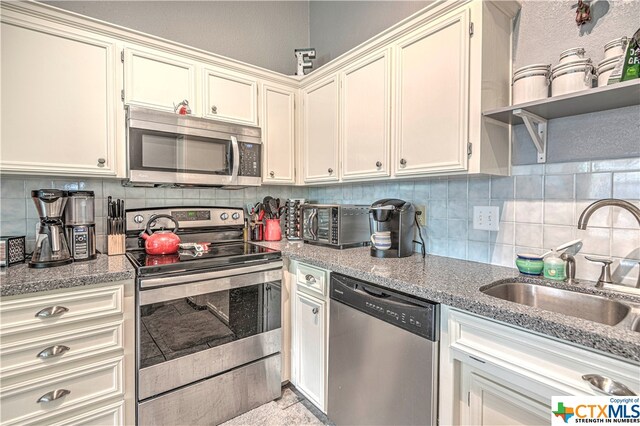 kitchen with cream cabinetry, appliances with stainless steel finishes, sink, and backsplash