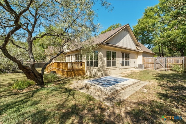 back of property featuring central AC unit, a patio area, a lawn, and a wooden deck