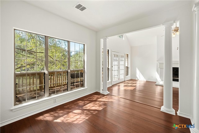 interior space with vaulted ceiling, wood-type flooring, french doors, and decorative columns