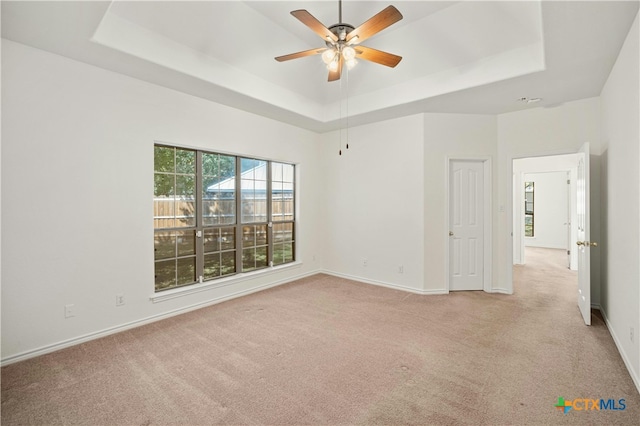 spare room with light carpet, a raised ceiling, and ceiling fan