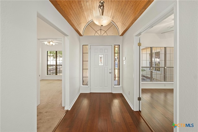 entrance foyer with wood ceiling, vaulted ceiling, carpet flooring, and ceiling fan