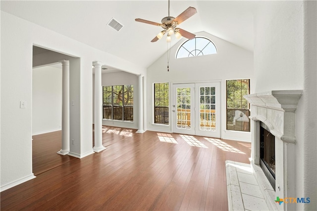 unfurnished living room featuring ceiling fan, high vaulted ceiling, wood-type flooring, decorative columns, and french doors