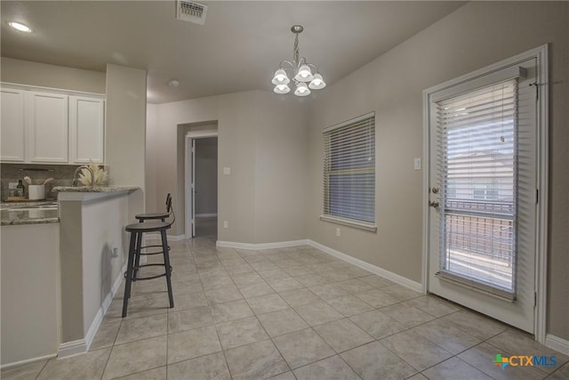 kitchen with light tile patterned flooring, white cabinetry, a chandelier, and decorative light fixtures