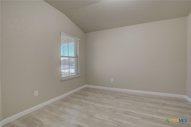 empty room featuring baseboards, lofted ceiling, and light wood-type flooring