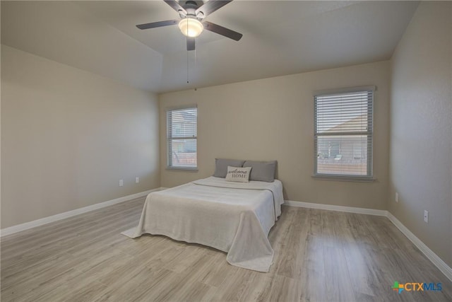 bedroom with light wood finished floors, a ceiling fan, and baseboards