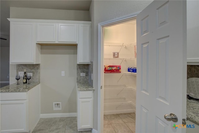 kitchen featuring tasteful backsplash, white cabinets, and light stone counters