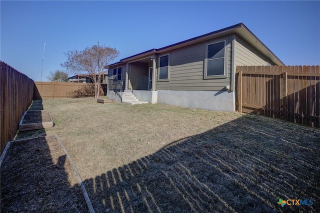 rear view of house with a yard and a fenced backyard