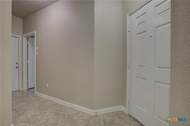 hall with baseboards and light tile patterned floors