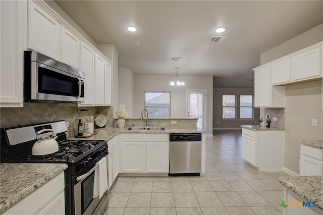 kitchen with a sink, visible vents, white cabinetry, backsplash, and appliances with stainless steel finishes