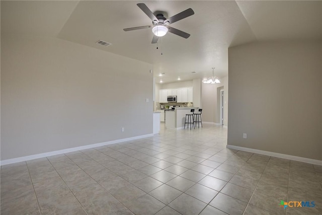 tiled empty room with ceiling fan with notable chandelier and lofted ceiling