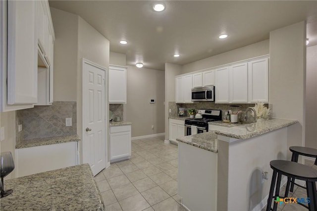 kitchen featuring backsplash, a peninsula, appliances with stainless steel finishes, and white cabinetry