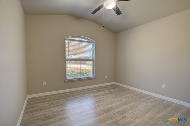 empty room featuring light wood-style flooring, baseboards, vaulted ceiling, and ceiling fan