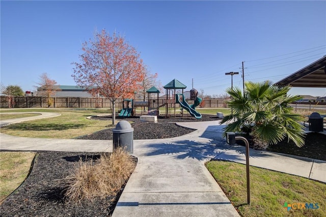 communal playground featuring a lawn and fence