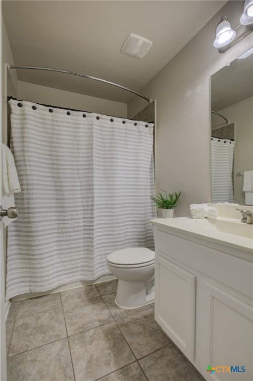 bathroom with tile patterned floors, toilet, vanity, and walk in shower