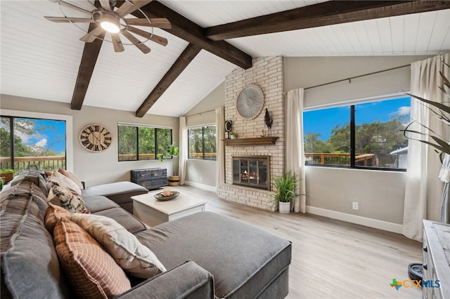 living room featuring vaulted ceiling with beams, ceiling fan, light hardwood / wood-style floors, and a brick fireplace