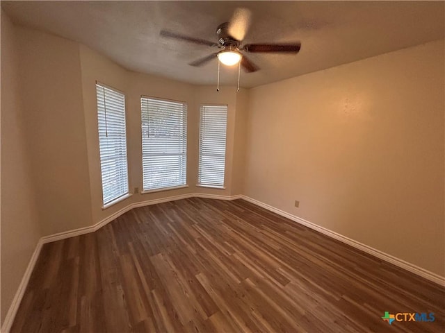 spare room with dark hardwood / wood-style flooring and ceiling fan