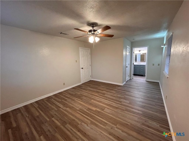 unfurnished room with a textured ceiling, ceiling fan, and dark wood-type flooring