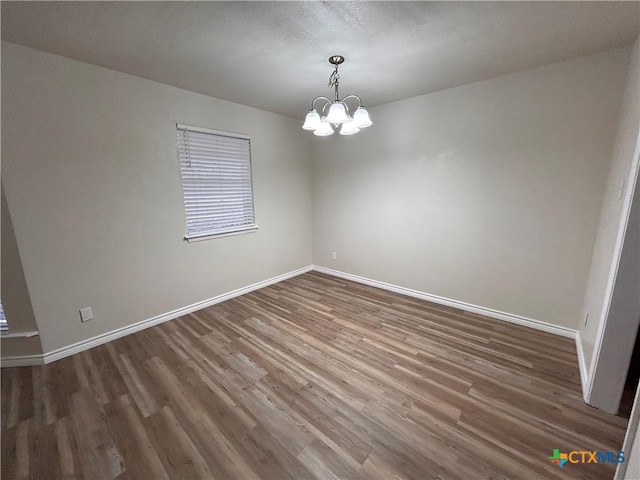 unfurnished room featuring dark wood-type flooring and a chandelier