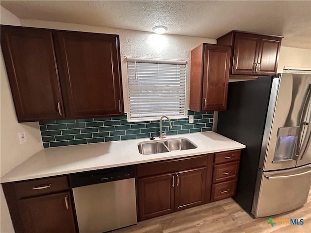 kitchen with decorative backsplash, appliances with stainless steel finishes, dark brown cabinetry, sink, and light hardwood / wood-style flooring