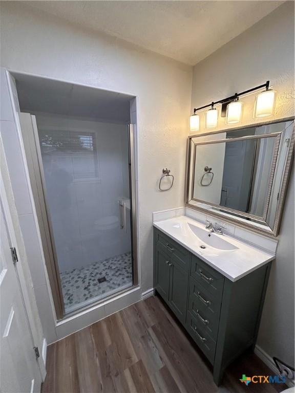 bathroom with hardwood / wood-style floors, vanity, and a shower with door