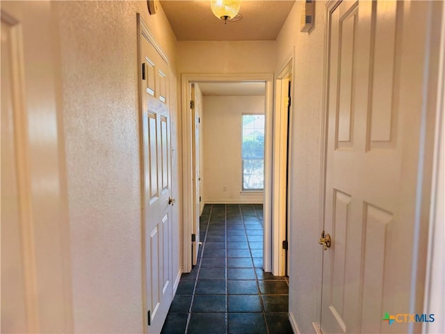 3900 Chisholm Trl, Salado, TX 76571 - hall with a textured wall, dark tile patterned flooring, and baseboards