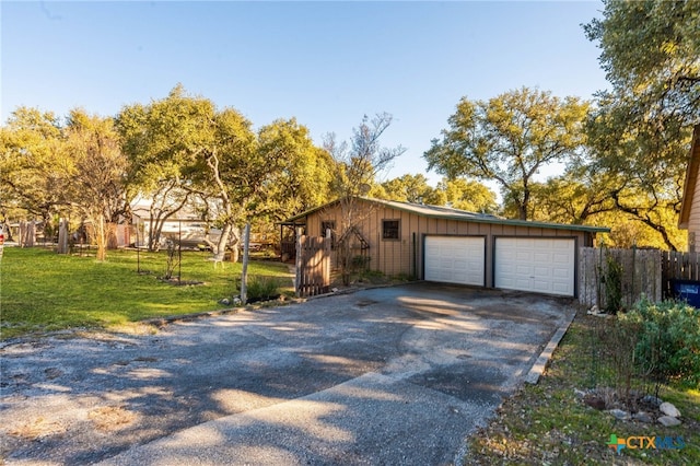 view of front facade featuring a detached garage, fence, an outdoor structure, board and batten siding, and a front yard