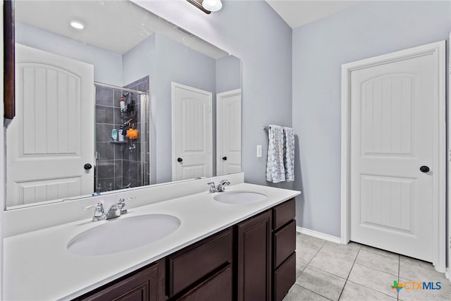 full bath featuring a sink, double vanity, a shower stall, and tile patterned flooring