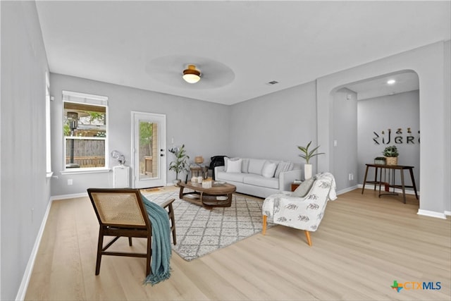 living room featuring visible vents, wood finished floors, baseboards, and arched walkways