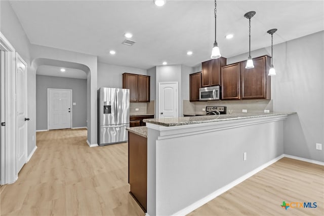 kitchen featuring light wood-type flooring, visible vents, stainless steel appliances, arched walkways, and a peninsula