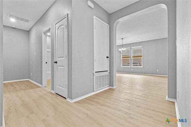 hall featuring a chandelier, visible vents, arched walkways, and wood finished floors