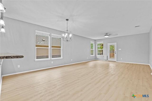 unfurnished living room with visible vents, baseboards, a notable chandelier, and wood finished floors