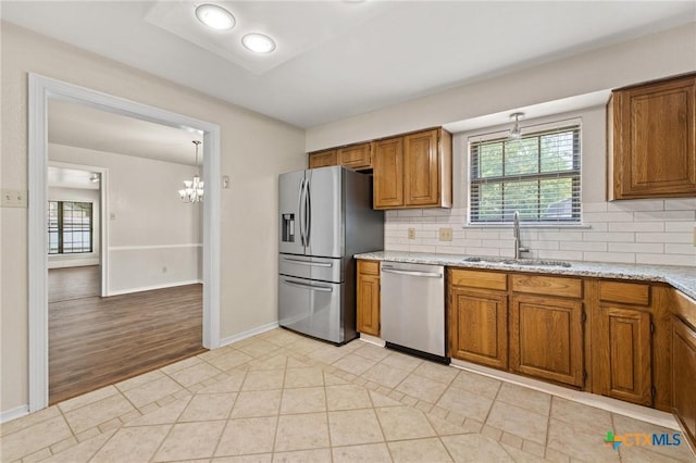 601 Pondview Dr, Killeen, TX 76542 - kitchen with stainless steel appliances, brown cabinetry, a chandelier, tasteful backsplash, and light tile patterned floors