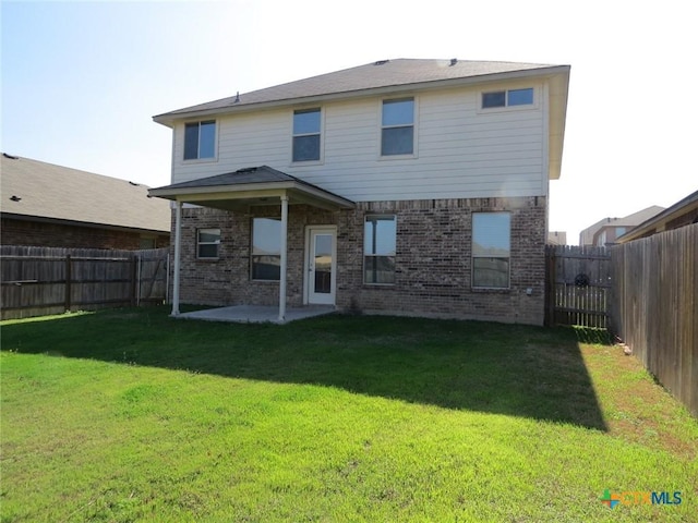 rear view of house with a patio area, a fenced backyard, a lawn, and brick siding