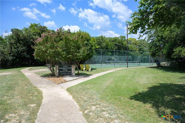 surrounding community featuring tennis court and a yard